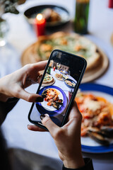 Capturing food photography with a smartphone at an elegant dinner table setting with gourmet dishes