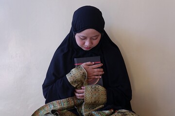 A Muslim woman holding the Koran happily