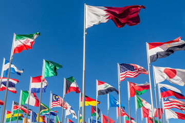 Many world countries national flags waving together on wind, Qatari flag in center and American, Iranian, Japanese, Chinese, Russian, Egyptian, Somalian, Saudi, Omani and other banners, Doha, Qatar