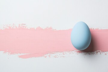 Blue egg on light pink brushstroke against white background for minimalist decor concept
