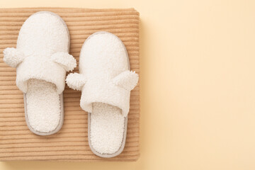 Soft teddy slippers on color background, top view