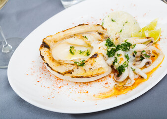 Grilled squid served with boiled rice, lime and garnished with chopped herbs
