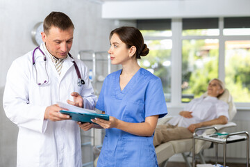 Obraz premium Two doctors are carefully examining the patient medical history