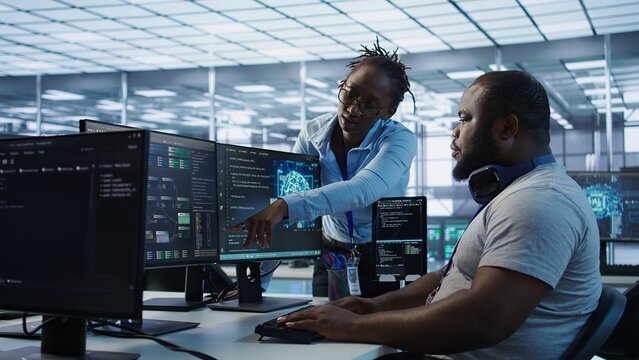 System administrator working with colleague in data center providing computing resources for different workloads. IT specialist talking with coworker while monitoring AI supercomputers, camera B