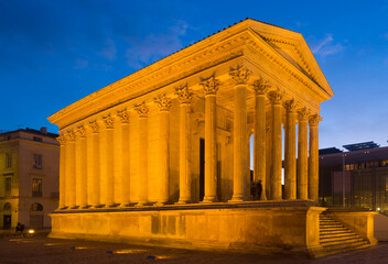 Obraz premium Night view of lighted Maison Carree of Nimes at dusk, France