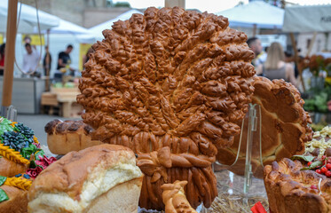 Artisanal baked bread with detailed decorations, prominently displayed at an outdoor market...