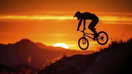 Bmx rider silhouette jumping at sunset with dramatic glowing background