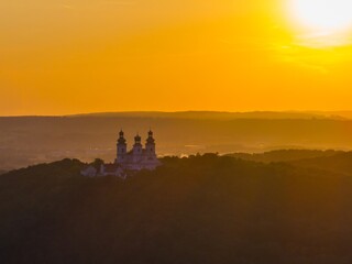 Fototapeta premium Sunset casts golden light over historic church atop a hill in the countryside