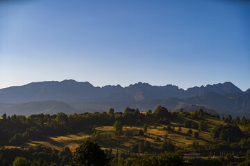 Morning light illuminates a serene mountain landscape with rolling hills and vibrant vegetation