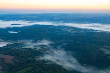 Morning mist blankets green hills in a scenic landscape at dawn near a rural area