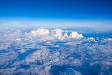 Vast expanse of clouds under a bright blue sky seen from above during daytime flight