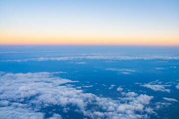 Sky above the clouds at sunset casts vibrant colors across the horizon during a tranquil flight