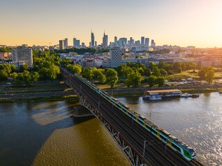 Vibrant sunset over the Vistula River with train crossing the bridge in Warsaw's skyline