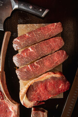 Assorted Cuts of Raw Meat with Knives, Charcoal, and Herbs on Rustic Background