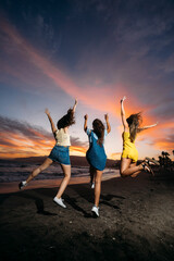 Three friends jumping on the beach at sunset