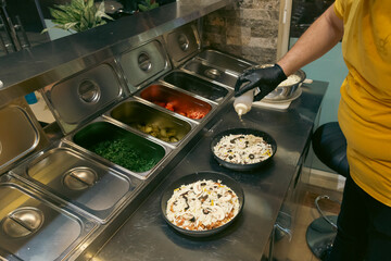 A chef preparing  pizzas in a fast food restaurant. 