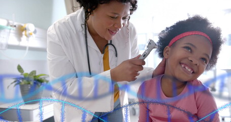 Image of dna strands over african american female doctor checking ear of happy girl patient