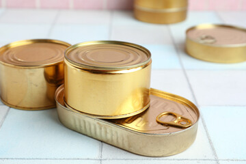 Tin cans with fish on white tiled table