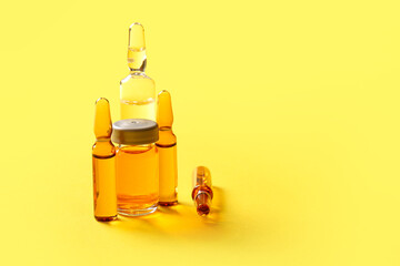 Medical ampules and bottle with medicines on yellow background