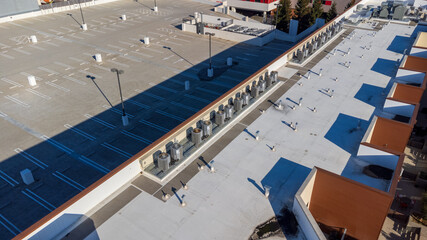 Obraz premium Aerial view of a large empty parking lot adjacent to a rooftop with HVAC units