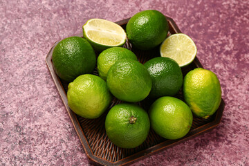 Tray with fresh limes on purple background
