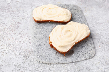 Board of tasty sandwiches with cream cheese on grey background