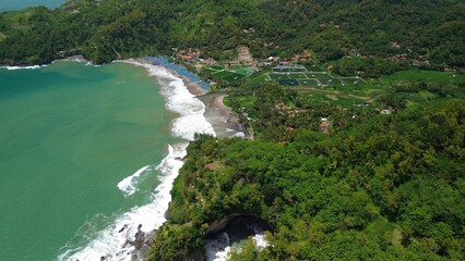 Aerial drone view of coastline with hills and trees, as well as view of coral cliffs and sea with waves from the ocean in Watu Bale  Beach Kebumen Central Java Indonesia