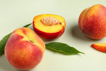 Sweet peaches and leaves on light background