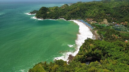 Aerial drone view of coastline with hills and trees, as well as view of coral cliffs and sea with waves from the ocean in Watu Bale  Beach Kebumen Central Java Indonesia