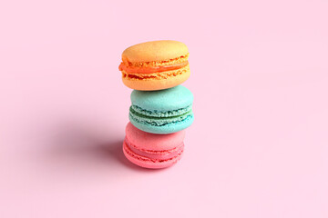 Different tasty sweet macaroons on pink background