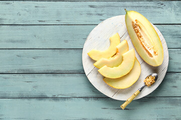 Board with pieces of sweet melon on blue wooden background