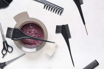 Bowl with hair dye and set of hairdresser's tools on white background