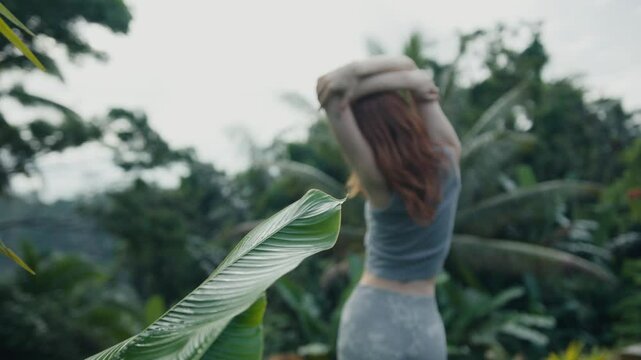 beautiful red-haire gitl doing stretching in the morning witho green jungle background on Bali