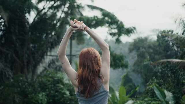 beautiful red-haire gitl doing stretching in the morning witho green jungle background on Bali