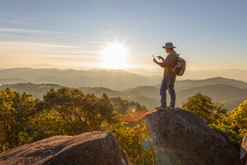 Hiker with backpack checks map on smartphone to find directions in wilderness area on top mountain.Hiker man hiking living healthy active lifestyle.
