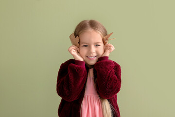 Happy little girl with autumn leaves on green background