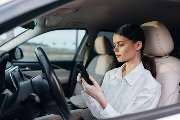 Woman, car, driver's seat, cell phone a woman sits in the driver's seat of her car, engrossed in her cell phone, intently looking at the screen, capturing a moment of multitasking and modern