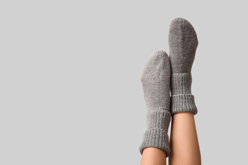 Legs of young woman in warm knitted socks on grey background