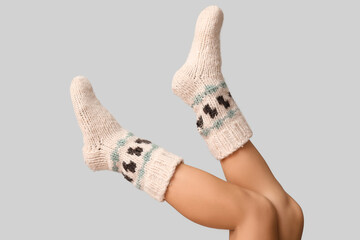 Legs of young woman in knitted socks on grey background