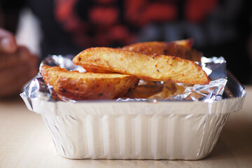 Deliciously Golden Crispy Potato Wedges Served in a Foil Container