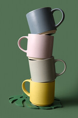 Stack of ceramic mugs on green background