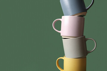 Stack of ceramic mugs on green background