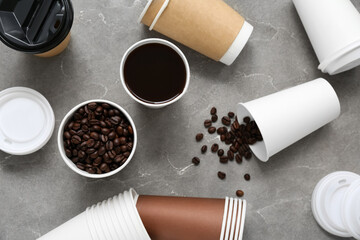 Different disposable cups of coffee on grey grunge background