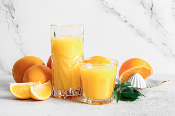 Glasses of fresh orange juice with fruits and juicer on white background