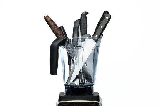 Kitchen knives in a clear plastic blender against a white backdrop