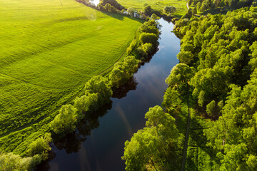 Obraz premium Colorful aerial view of green agricultural field near river bed