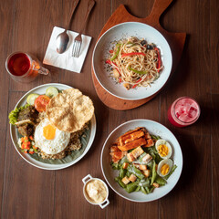 A welcoming table features rice with fried egg, grilled chicken and veggies, plus tasty pasta and refreshing drinks
