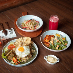 Enjoying a variety of flavorful dishes, including fried rice topped with a sunny-side-up egg, grilled chicken, pasta, and a vibrant pink drink