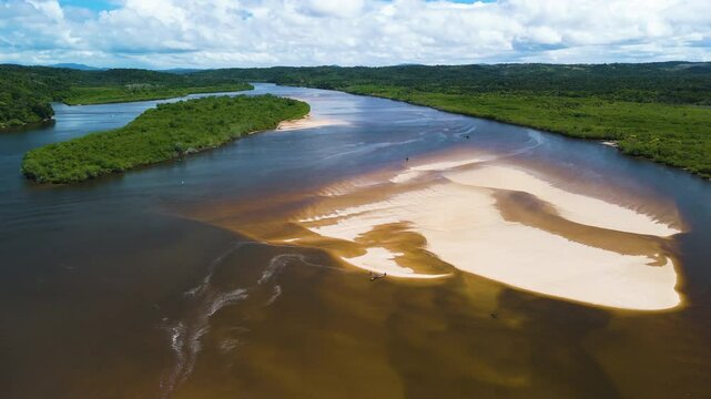 Drone approaching people with a boat landed on a sandbank in Itacare, Brazil