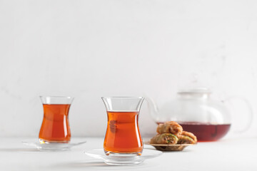 Glasses of Turkish tea with teapot and tasty baklava on white background